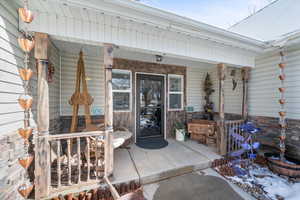 View of exterior entry featuring covered porch and stone siding