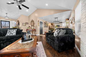 Living area with dark wood-style flooring, a ceiling fan, lofted ceiling, and hanging lights