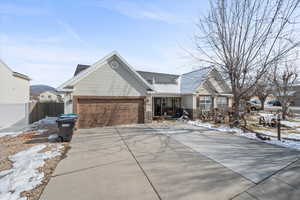 View of front of home featuring driveway, a porch, an attached garage, and stone siding