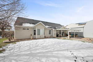 Snow covered back of property featuring a patio and roof with shingles
