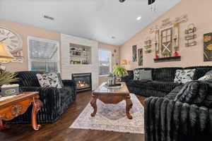 Living area featuring lofted ceiling, a large fireplace, dark wood finished floors, ceiling fan, and recessed lighting