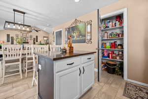 Kitchen featuring white cabinets, pendant lighting, a center island, a ceiling fan, and vaulted ceiling