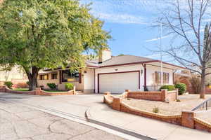 Ranch-style house featuring an attached garage, concrete driveway, a chimney, a shingled roof, and brick siding