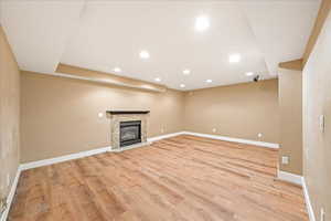 Unfurnished living room featuring recessed lighting, a glass covered fireplace, and light wood-type flooring