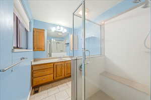 Bathroom with vanity, a shower stall, and light tile patterned flooring