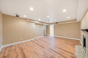 Unfurnished living room with recessed lighting, light wood-style floors, and a fireplace with flush hearth