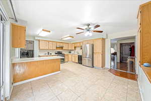Kitchen with light countertops, stainless steel appliances, a peninsula, ceiling fan, and independent washer and dryer