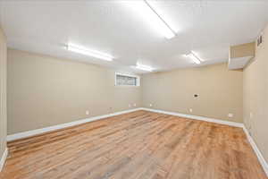 Basement with light wood finished floors and a textured ceiling