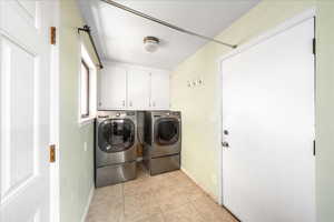 Laundry room with cabinet space, light tile patterned flooring, and separate washer and dryer