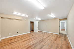 Finished basement featuring light wood-style floors and a textured ceiling