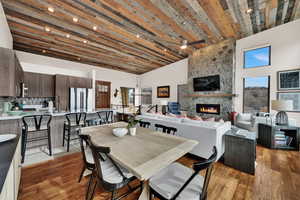 Dining room featuring a fireplace, light wood-style flooring, ceiling fan, and a high wooden ceiling
