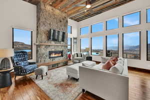 Living area featuring a fireplace, hardwood / wood-style flooring, a ceiling fan, and a high wooden ceiling