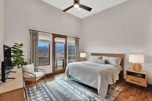 Bedroom featuring access to exterior, wood finished floors, a high ceiling, a ceiling fan, and a mountain view