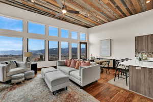 Living room with dark wood-type flooring, a ceiling fan, a mountain view, a high ceiling, and recessed lighting