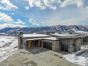 View of front of house featuring a mountain view, a chimney, and stone siding