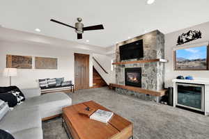 Carpeted living area with a stone fireplace and a ceiling fan