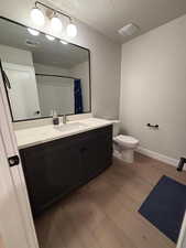 Bathroom featuring vanity, dark wood finished floors, curtained shower, and a textured ceiling