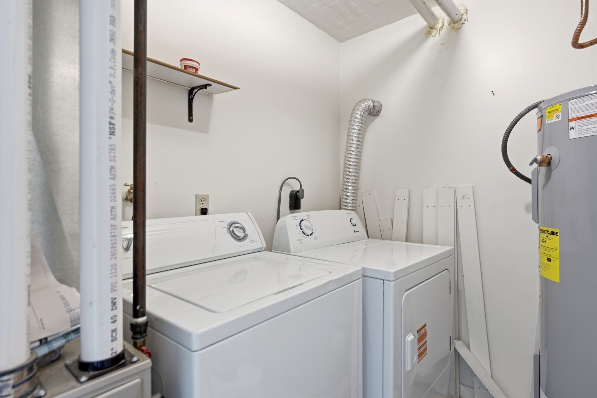Dedicated utility space featuring a washer and dryer, water heater, and wall-mounted shelving