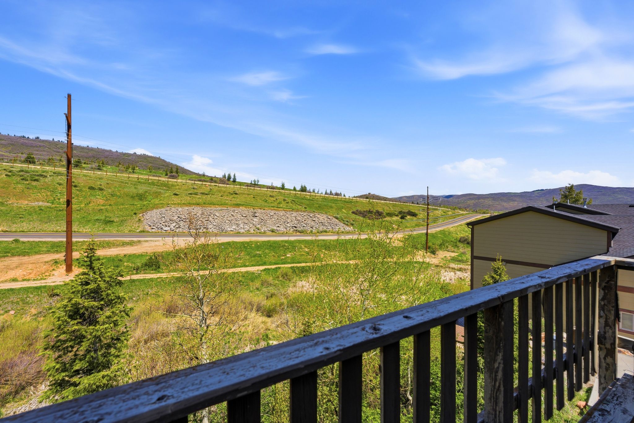 Deck railing overlooking a natural landscape with rolling hills and distant mountains