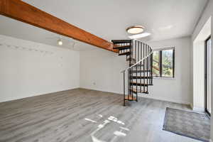 Entryway featuring beam ceiling, light wood-style floors, and rail lighting