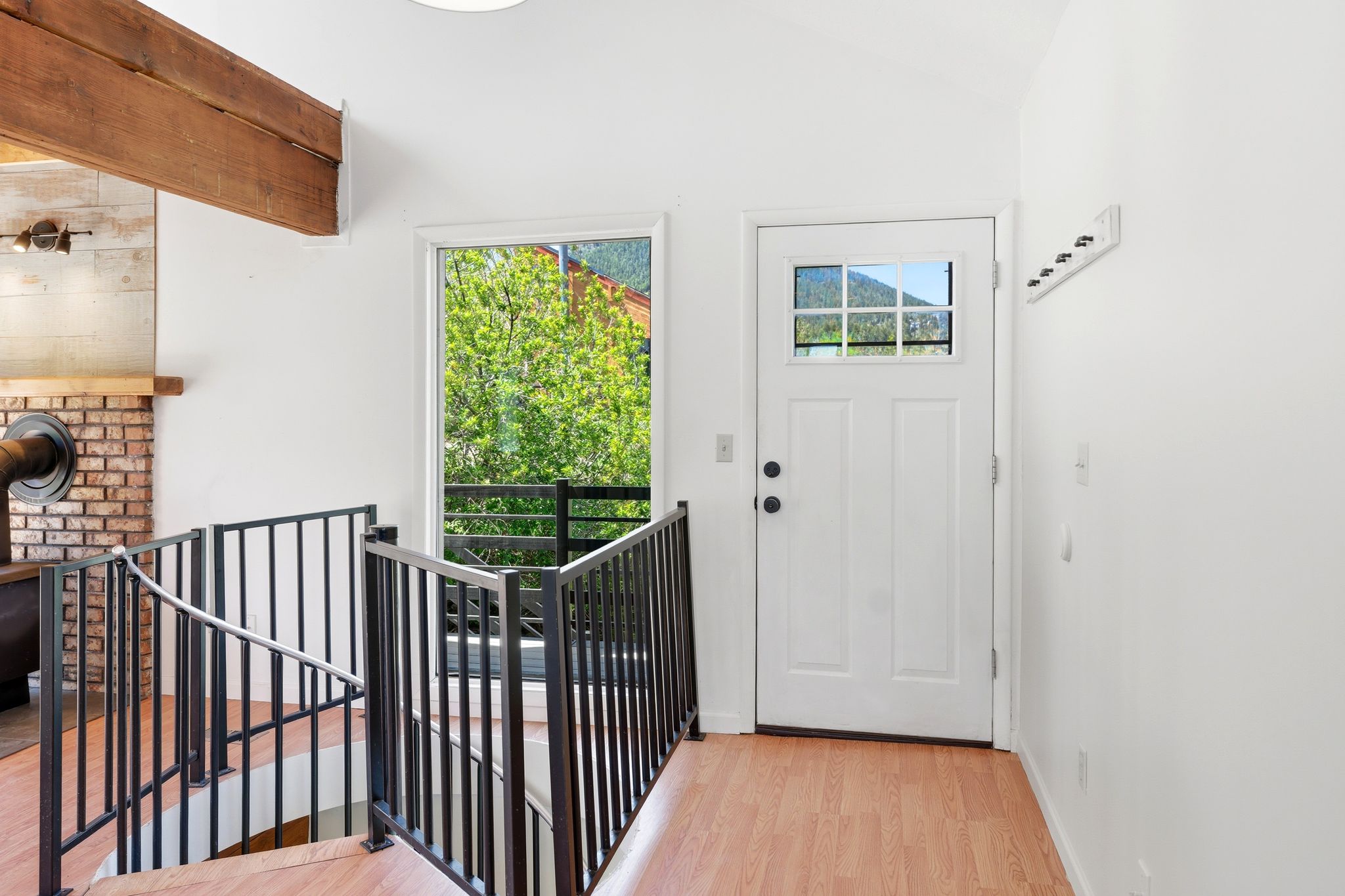 Entryway featuring wood-finish flooring, a white paneled door with grid-patterned glass, and a black wrought iron staircase railing