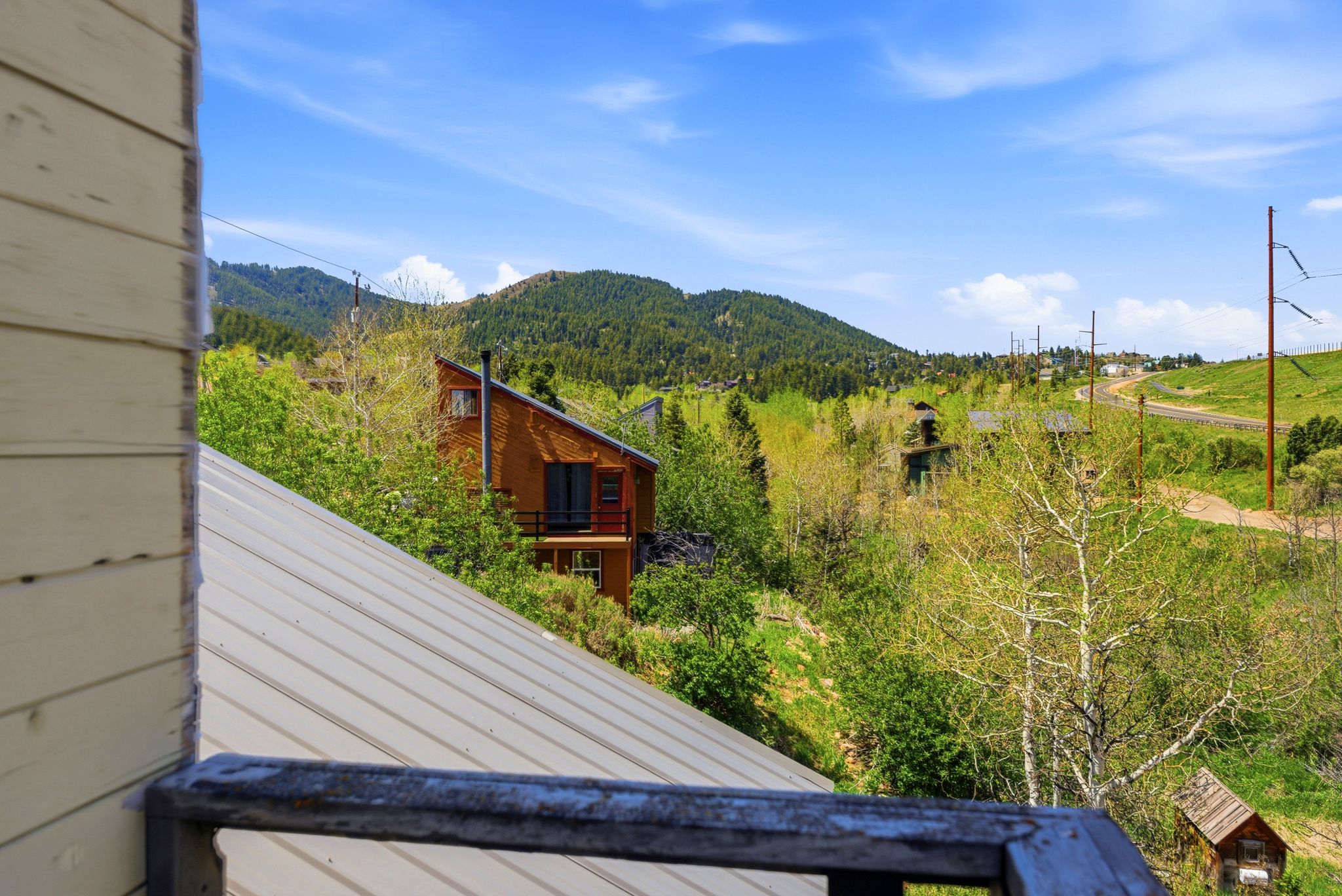 Hillside property featuring a brown exterior with an A-frame roof and an exterior balcony