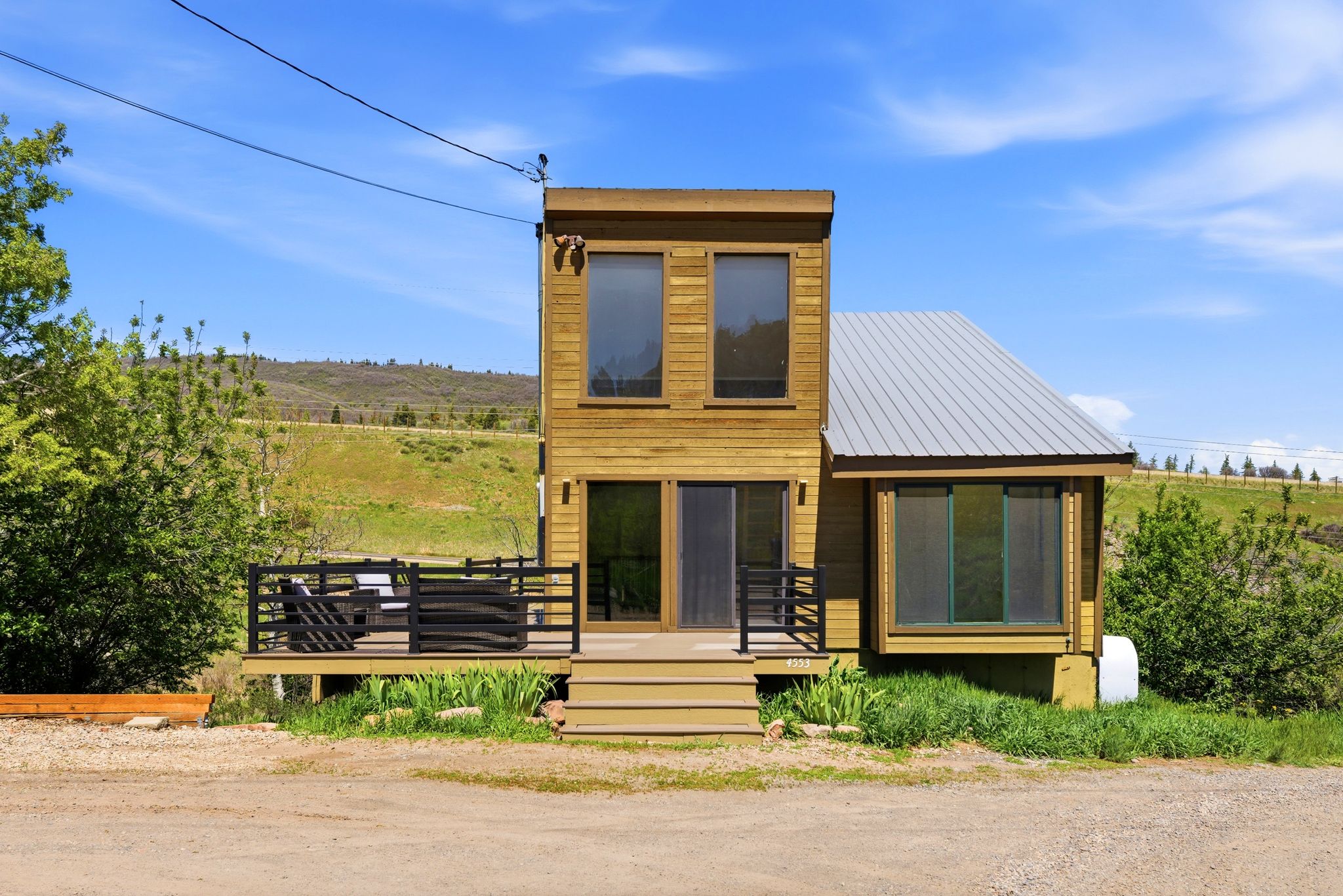 Contemporary-style home featuring wood siding, a metal roof, and a two-story elevation