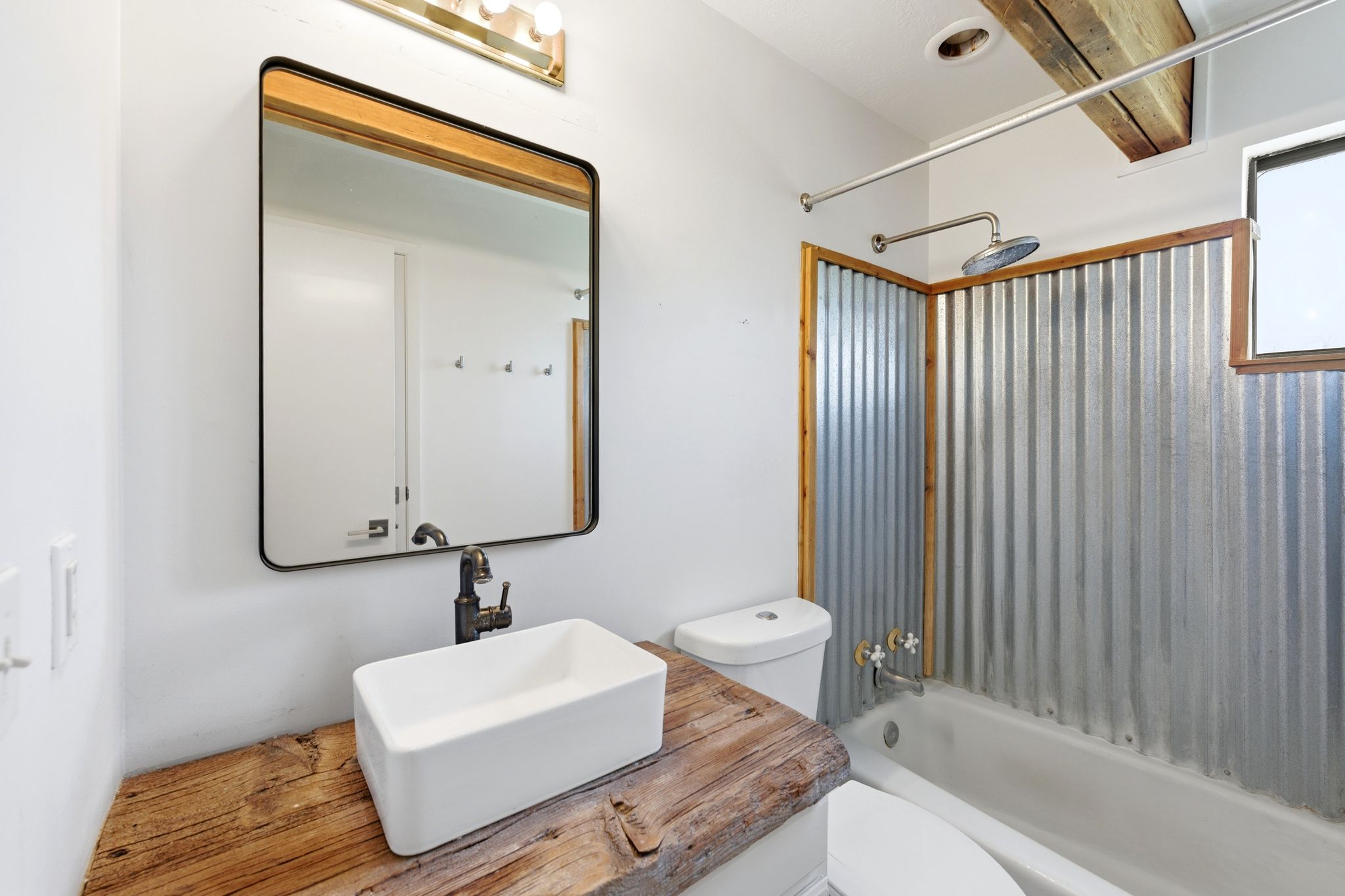 Bathroom featuring a solid wood-finish vanity countertop with a rectangular vessel sink and dark-finish faucet