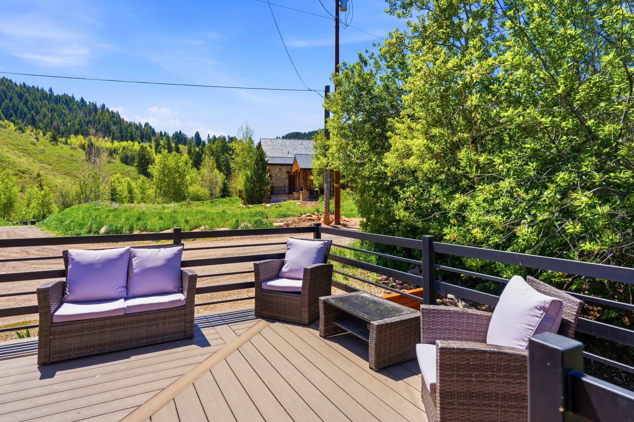 Exterior deck with composite decking, black railing, and a mountainous, treed backdrop