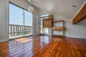 Unfurnished living room featuring hardwood / wood-style flooring and vaulted ceiling