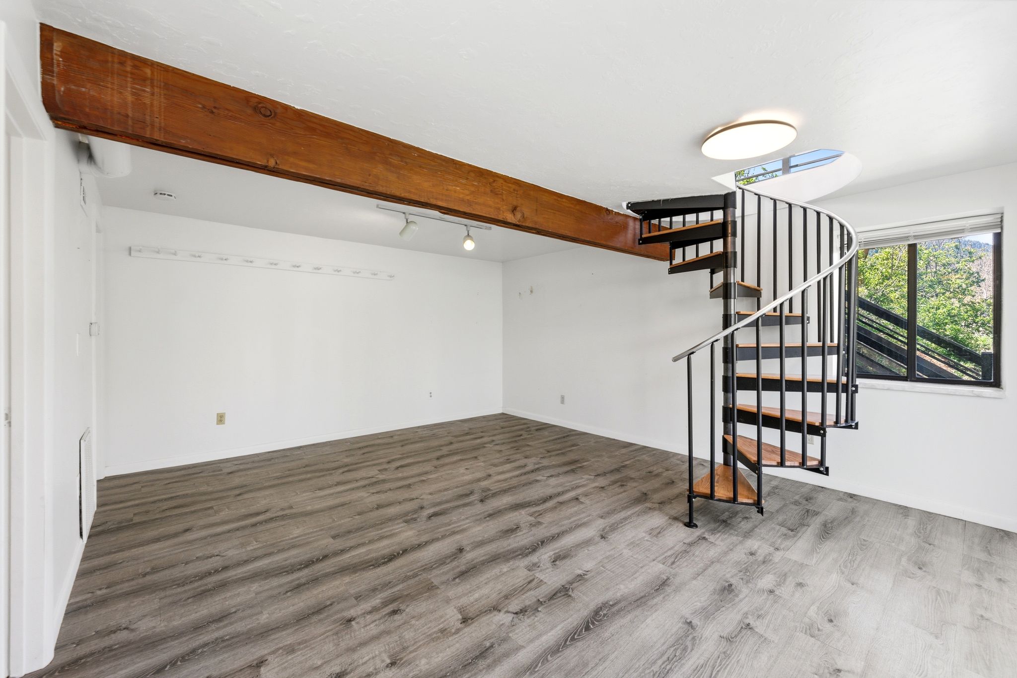 Spiral staircase with black metal railings and wood-finish treads