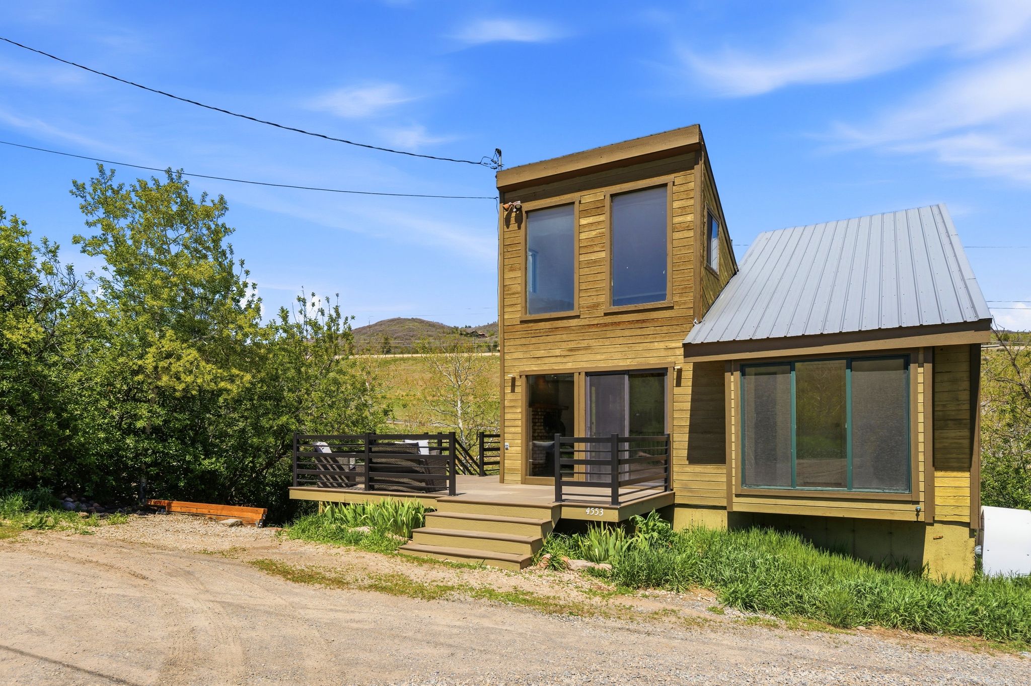 Contemporary two-story residence featuring wood-paneled siding and a contrasting metal roof