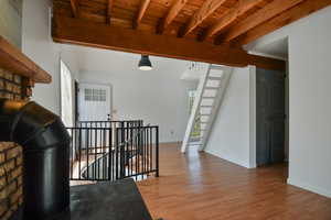 Stairway with healthy amount of natural light, wood finished floors, and a wood ceiling with exposed beams