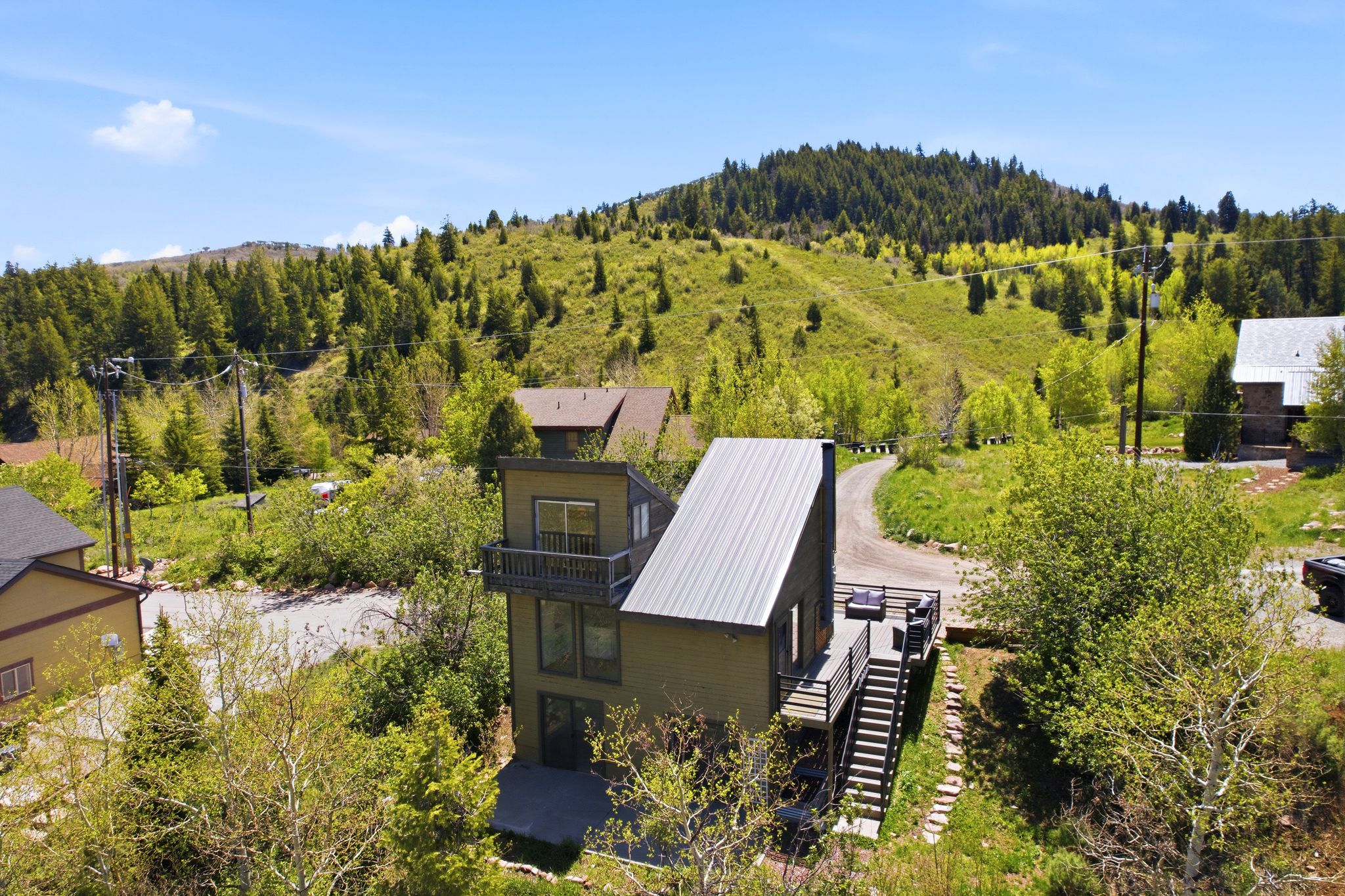 Modern exterior featuring a metal roof, multiple outdoor decks, and a hillside setting