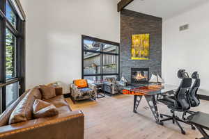 Home office with light wood finished floors, a fireplace, and vaulted ceiling