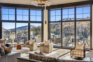 Living area featuring a mountain view, plenty of natural light, a high ceiling, and stone finish floors