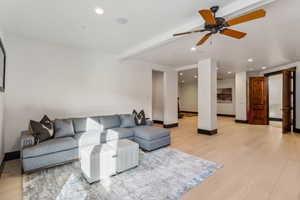 Living room with light wood-type flooring, beamed ceiling, ceiling fan, and recessed lighting