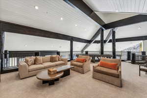 Carpeted living room featuring lofted ceiling with beams and expansive windows