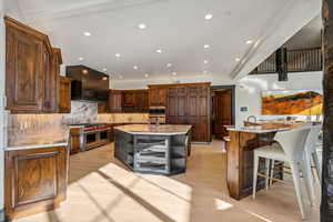Kitchen with open shelves, light stone counters, stainless steel appliances, recessed lighting, and a kitchen breakfast bar