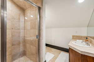 Full bathroom with vanity, a stall shower, and vaulted ceiling