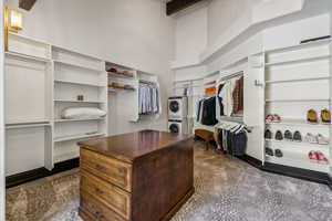 Walk in closet with stacked washing machine and dryer and a high ceiling