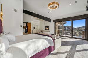 Bedroom with a mountain view, a large fireplace, access to exterior, recessed lighting, and vaulted ceiling