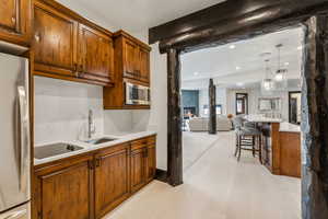 Kitchen with open floor plan, wood finish cabinets, freestanding refrigerator, beamed ceiling, and hanging light fixtures