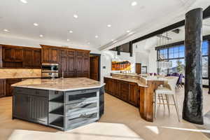 Kitchen with open shelves, light stone counters, a kitchen breakfast bar, beam ceiling, and recessed lighting