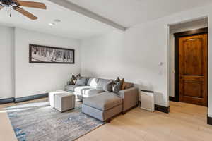 Living area with a ceiling fan, light wood-style floors, beam ceiling, and recessed lighting