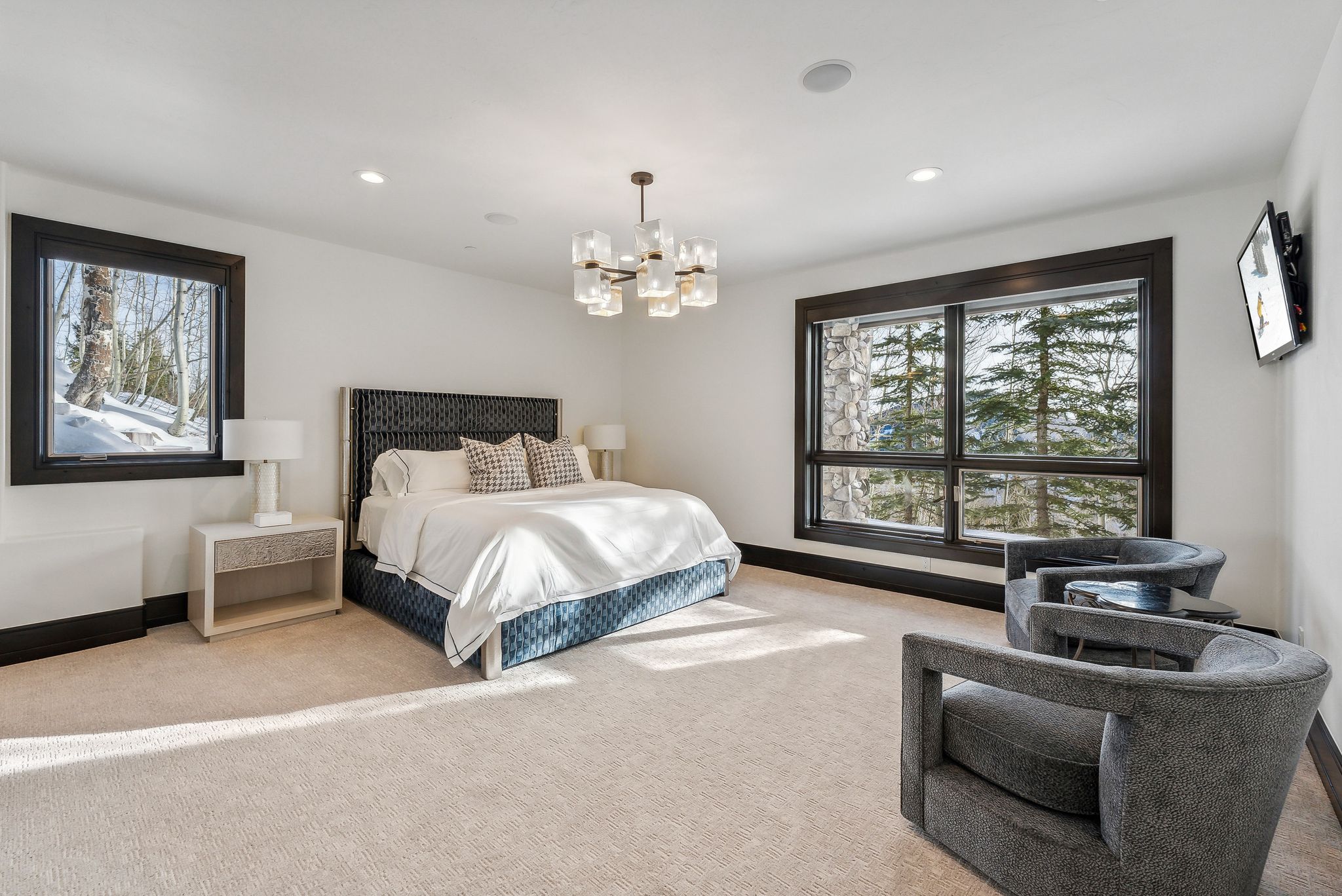 Carpeted bedroom with multiple windows and a chandelier