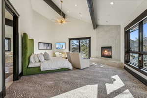 Bedroom with a high end fireplace, suspended lighting, and vaulted ceiling