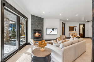 Living area with a stone fireplace, light colored carpet, and recessed lighting