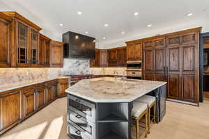 Kitchen featuring open shelves, light stone counters, an island with sink, recessed lighting, and glass insert cabinets