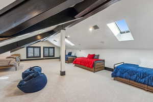 Carpeted bedroom featuring a skylight and beamed ceiling